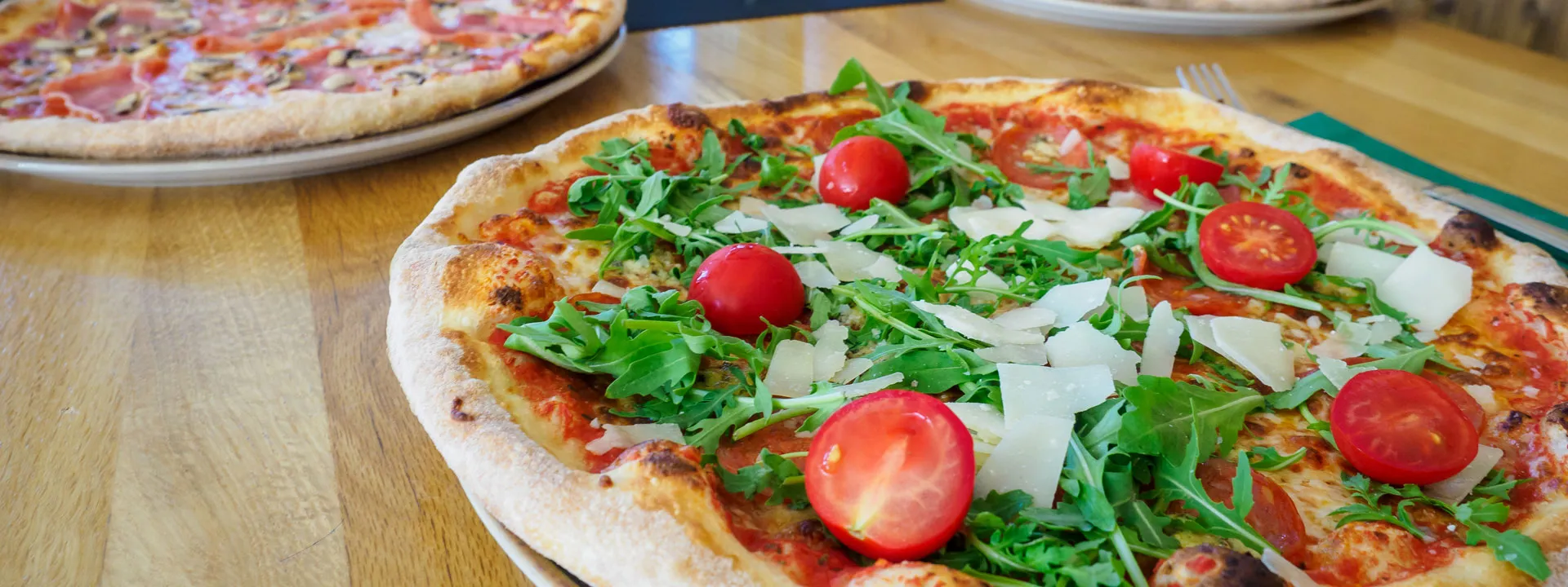 Pizza belegt mit Tomaten, Rucula und Parmesan